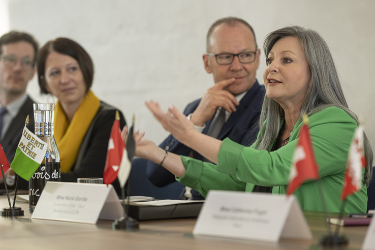 Madame Gorrite fait un geste avec les deux bras, assise derrière une table aux côtés de son collègue genevois Serge Dal Busco.