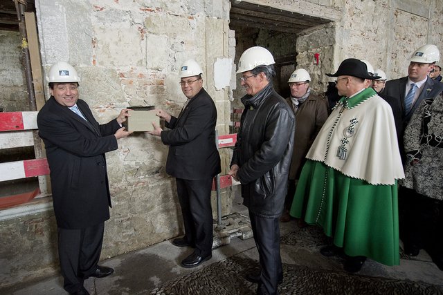 Les personnages coiffés de casques tiennent la pierre gravée qui sera scellée.