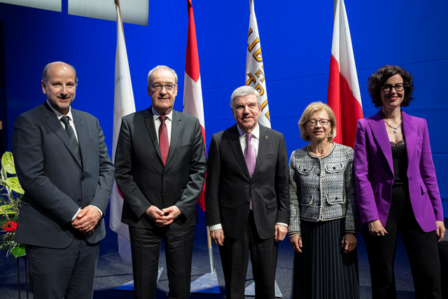 Les personnages posent côte à côte; derrière eux, des drapeaux.