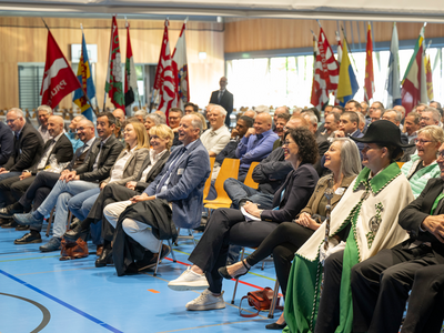 plusieurs membres du Conseil d'Etat ainsi que des invités assis, assitent à un discours et rient.