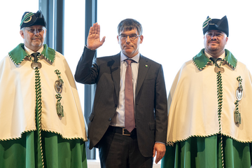 Il lève la main lors de la prestation, entre deux huissiers en grande tenue.