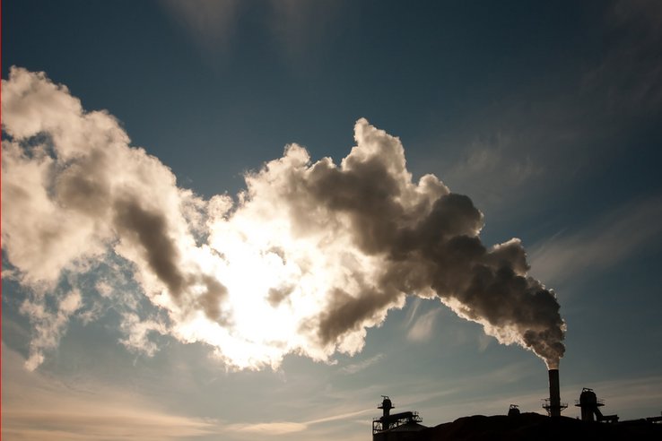cheminée d'usine avec fumée sur fond de ciel bleu
