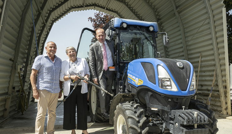 Les trois personnages sont sous le couvert de la station de lavage. Madame Métraux tient la buse de rinçage, près d'un tracteur sur lequel monsieur Leuba se tient debout.