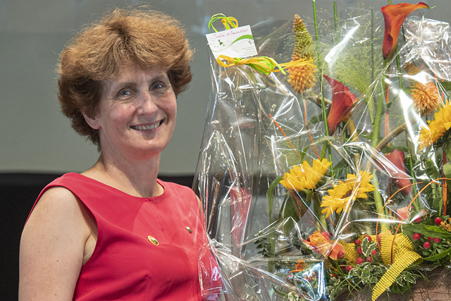 Madame Butera pose avec un bouquet de fleurs.