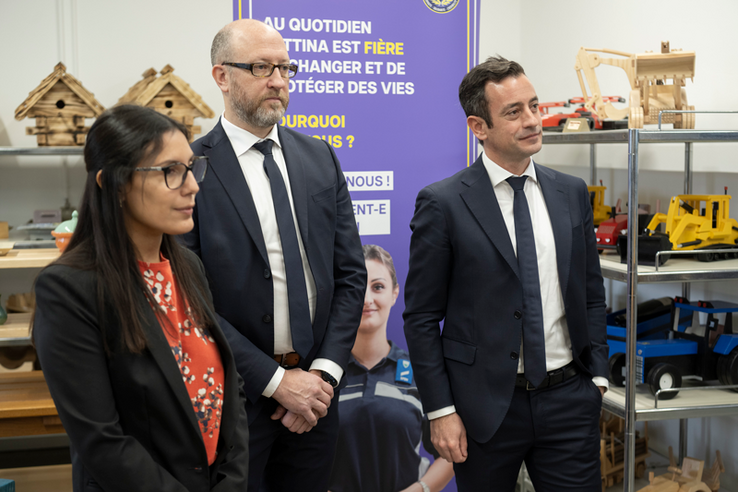 Les personnes posent. Derrière elles, des rayonnages avec des produits manufcaturés en bois par les personnes en détention (maisons pour oiseaux, jouets d'enfants...)