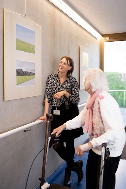 La médiatrice et une personne regardent les images accrochées au mur