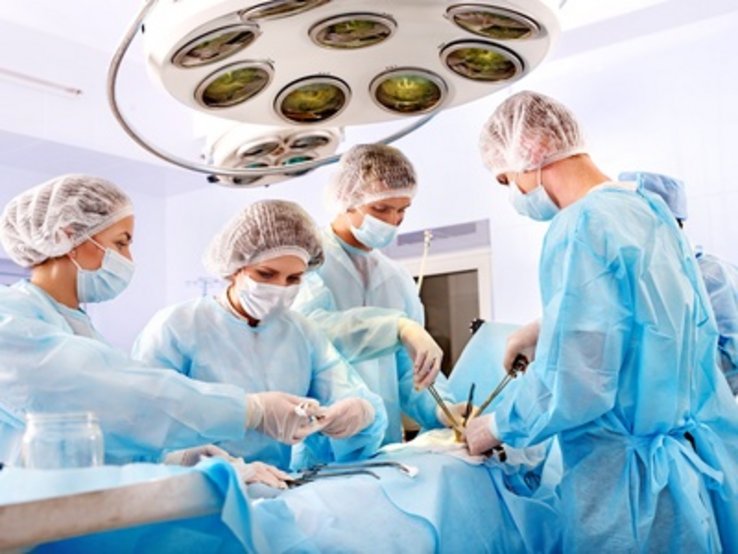 Vue d'une salle d'opération: personnel médical en tenue chirurgicale au travail autour de la table d'opération.