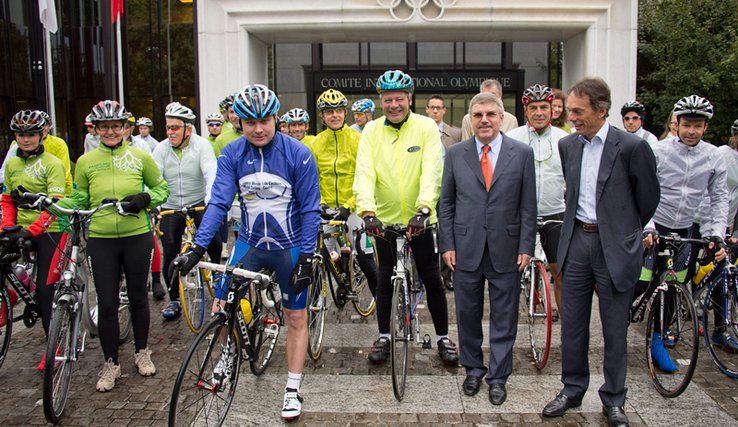 Les cyclistes prêts au départ, devant l'entrée du bâtiment du céio, sous la pluie.