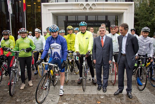 Les cyclistes prêts au départ, devant l'entrée du bâtiment du céio, sous la pluie.