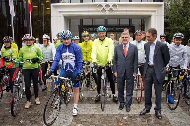 Les cyclistes prêts au départ, devant l'entrée du bâtiment du céio, sous la pluie.