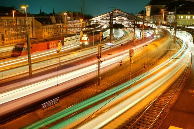 La marquise de la gare de nuit avec des trains en mouvement.