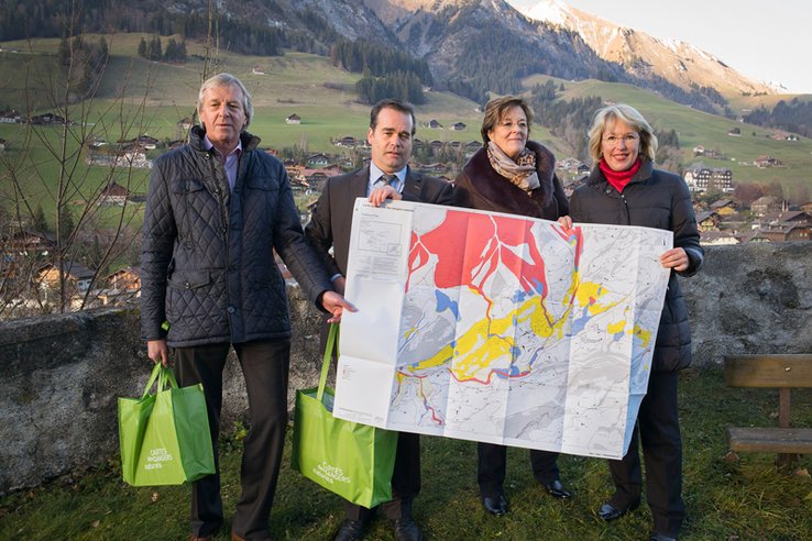 Les personnages posent en tenant la carte sur fond de montagnes.