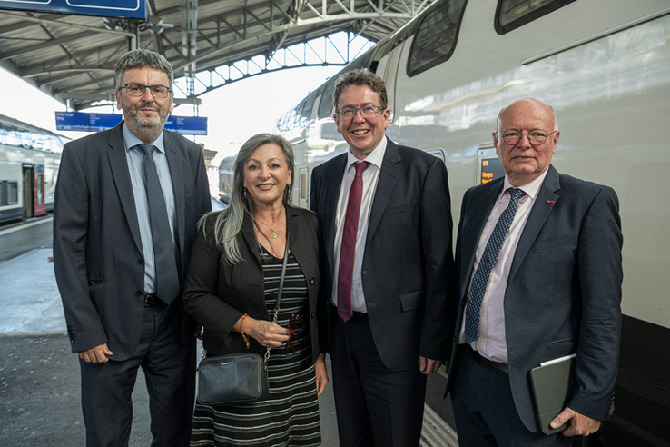 Les personnages posent sur un quai de la gare de Lausanne. Derrière eux, un train.
