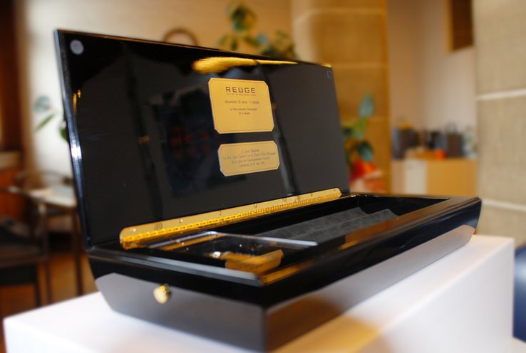 Photo de la boîte à musique Reuge, couvercle ouvert avec sur une plaquette le message du Conseil d'Etat.