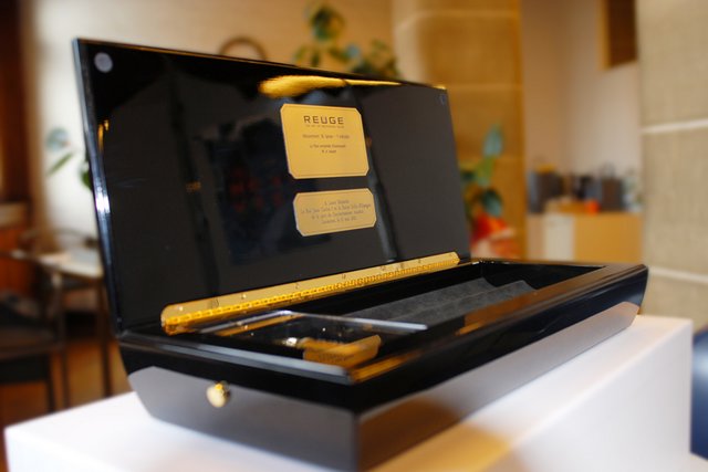 Photo de la boîte à musique Reuge, couvercle ouvert avec sur une plaquette le message du Conseil d'Etat.