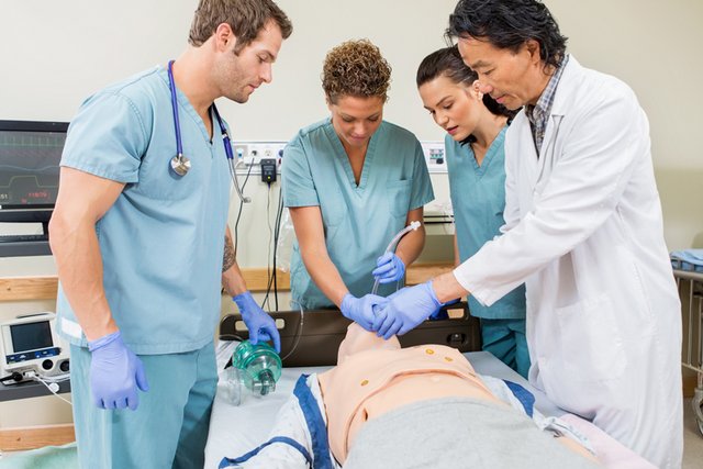 Des élèves infirmiers et un instructeur en tenue s'affairent autour d'un faux malade (poupée).