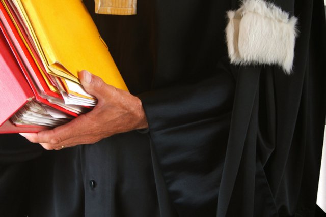 Image d'illustration: un avocat en robe, une pile de dossiers dans ses bras.