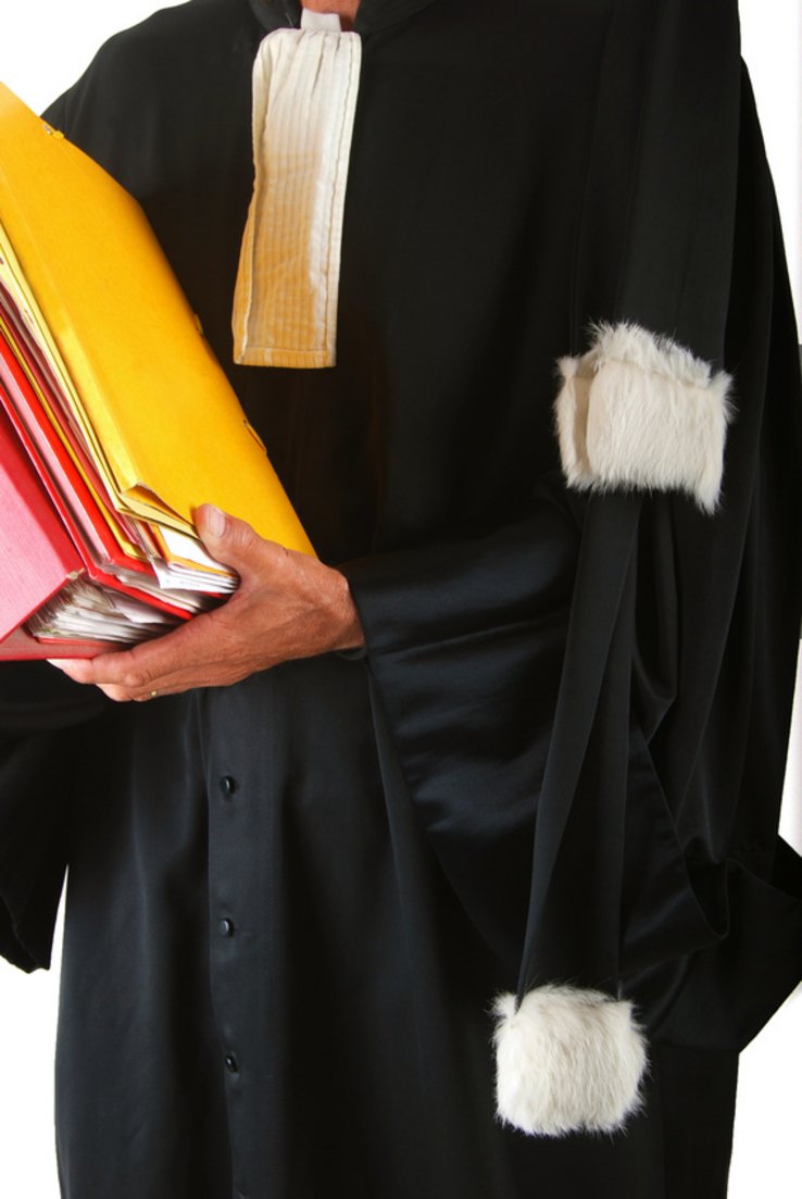 Image d'illustration: un avocat en robe, une pile de dossiers dans ses bras.