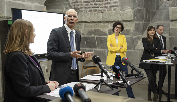 Me Daniel Schafer, avocat, expert fiscal diplômé, lors de la conférence de presse du 23 mars. L'avocat est au centre en train de parler, madame Dittli à gauche. La présidente du Conseil d'Etat Christelle Luisier, sa collègue Rebecca Ruiz et le chancelier Aurélien Buffat sont droite, plus au fond.