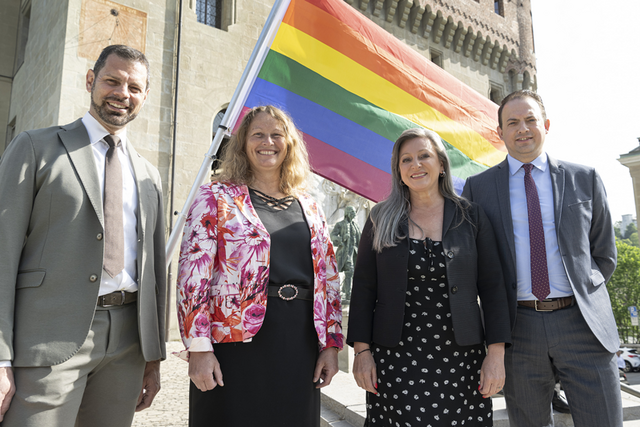 Les quatre personnes posent devant le drapeau arc-en-ciel, devant le château Saint-Maire..