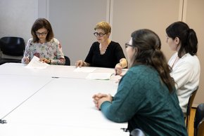 Les personnes sont assises autour d'une table, l'une tient un document.