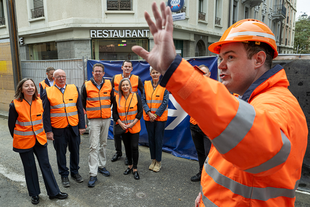 Photo prise rue du Simplon. Tout le monde porte des vêtements haute visibilité orange.
