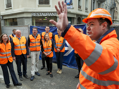 Photo prise rue du Simplon. Tout le monde porte des vêtements haute visibilité orange. 