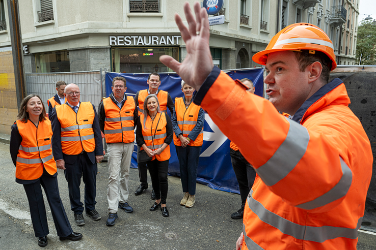 Photo prise rue du Simplon. Tout le monde porte des vêtements haute visibilité orange. 