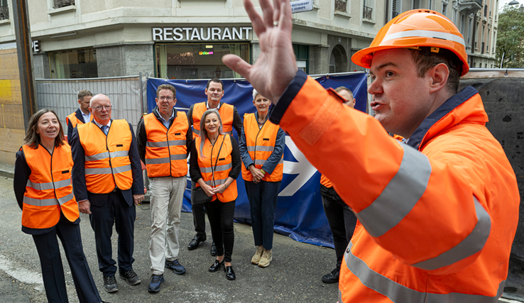Photo prise rue du Simplon. Tout le monde porte des vêtements haute visibilité orange. 