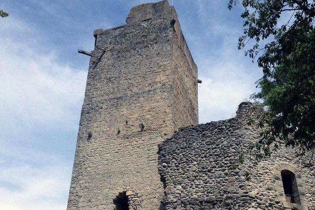 L'édifice sur sa colline. Une tour carrée faites de pierres assemblées. Accolée: la ruine d'un autre bâtiment avec encore une fenêtre.