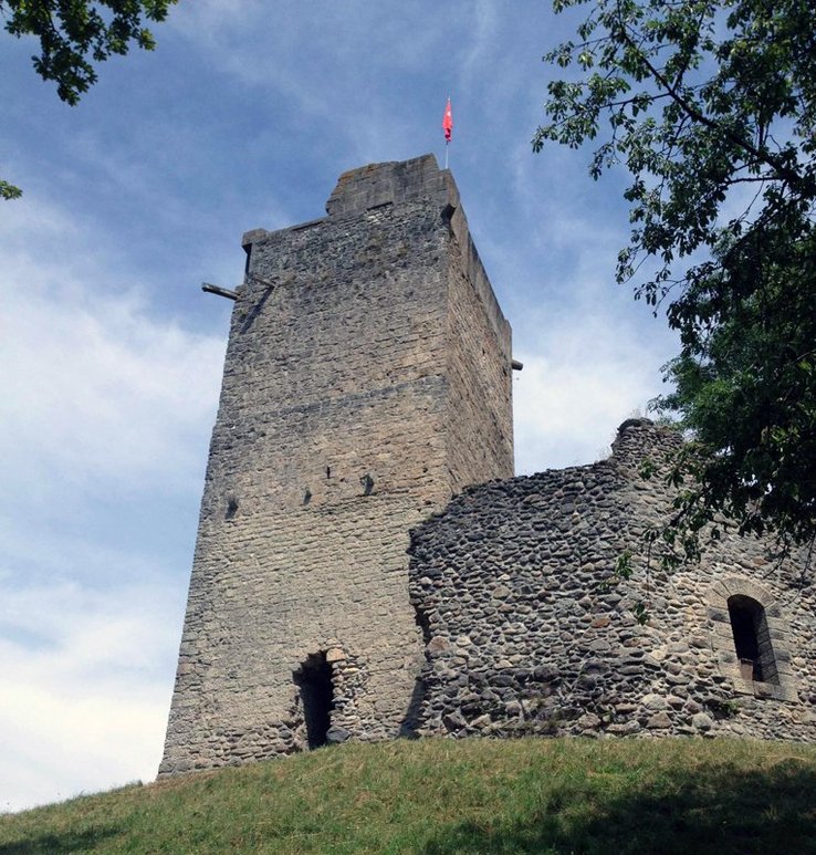 L'édifice sur sa colline. Une tour carrée faites de pierres assemblées. Accolée: la ruine d'un autre bâtiment avec encore une fenêtre.