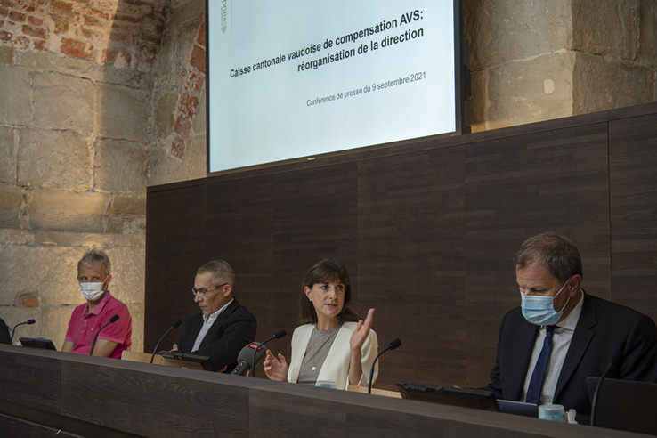 Photo prise durant la conférence de presse. La conseillère d'Etat parle. Derrière les personnages, un grand écran.