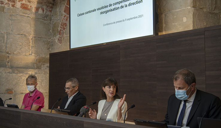 Photo prise durant la conférence de presse. La conseillère d'Etat parle. Derrière les personnages, un grand écran. 