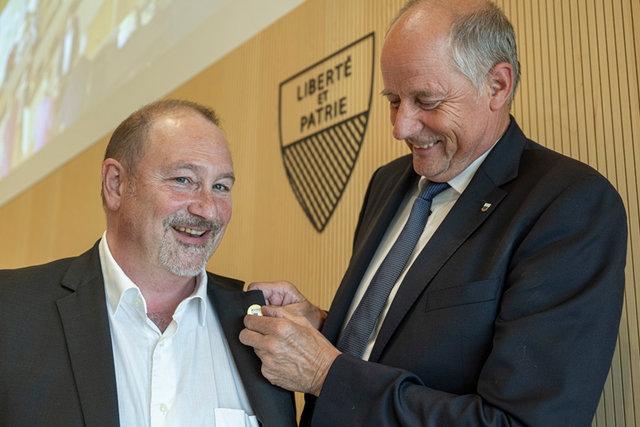 Monsieur Thuillard fixe un pins au revers du veston de son successeur.