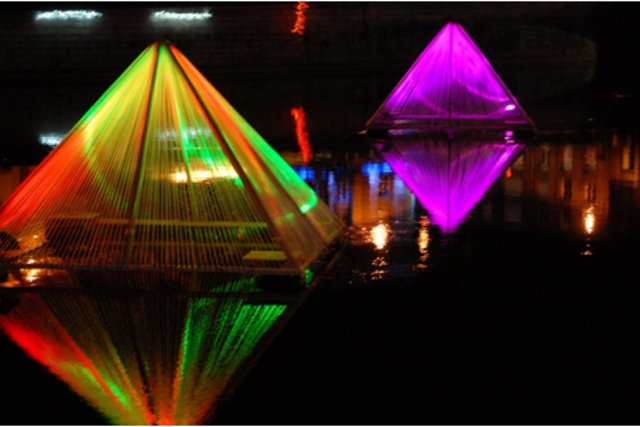 Des pyramides lumineuses apparaissant posées sur l'eau.