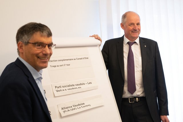 Les 2 candidats devant le panneau d'affichage du résultat du tirage au sort