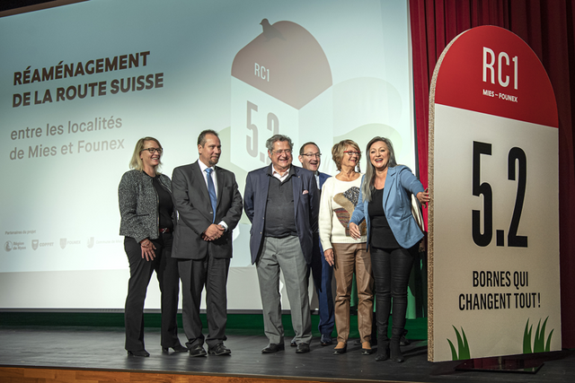 Les personnages sur une scène à côté d'une borne géante en carton sur laquelle on lit: "RC 1, 5,2 bornes qui changen tout".