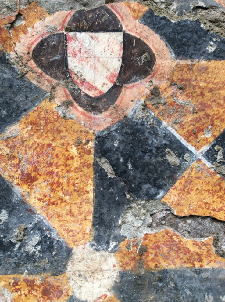 On distingue des formes géométriques et le blason d'une famille. Les couleurs vives sont passées.