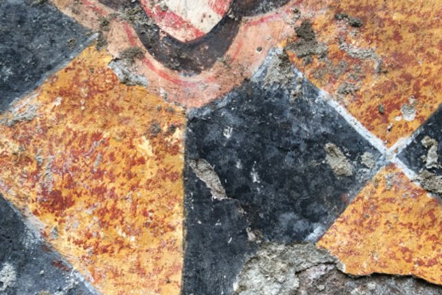 On distingue des formes géométriques et le blason d'une famille. Les couleurs vives sont passées.