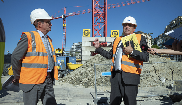 Les deux personnes sur le chantier des musées de Plateforme 10. Un micro est tendu devant monsieur Broulis.