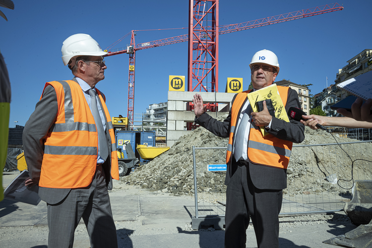 Les deux personnes sur le chantier des musées de Plateforme 10. Un micro est tendu devant monsieur Broulis.