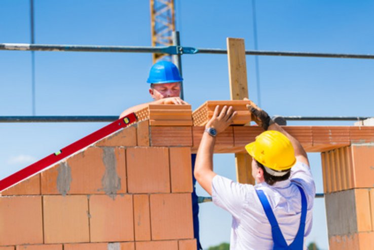 Deux maçons occupés au montage d'un mur de briques sur un chantier.