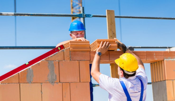 Deux maçons occupés au montage d'un mur de briques sur un chantier.