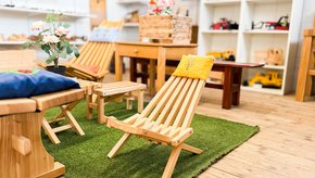 différents meubles arrangés comme dans un salon privé. Chaises, table basse avec plante. Au fond, des étagères, floues.
