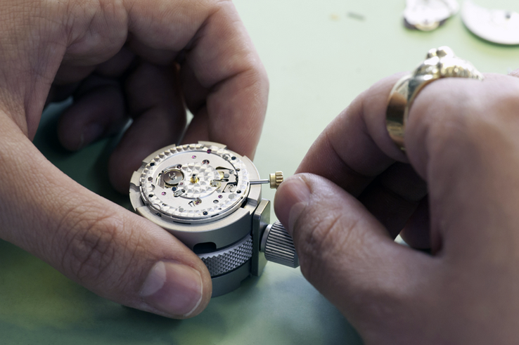 Illustration: mains d'une horlogère travaillant une pièce