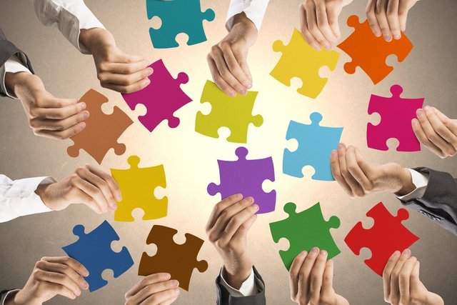 Image d'illustration: des mains disposées en cercle tendent des pièces de puzzle colorées.