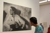 Un jeune visiteur regarde une grande photo exposée, tête penchée. 