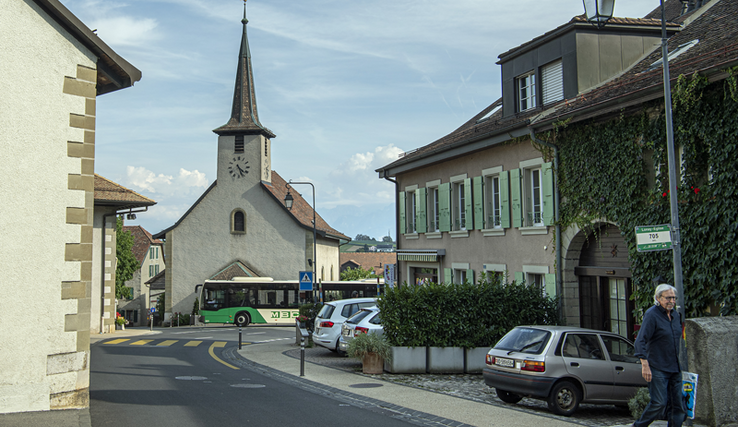 Vue du centre du village de Lonay, avec un passant et un bus