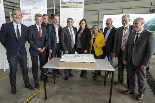 Les dix personnes posent derrière la maquette du futur centre, dans une halle des locaux actuels.