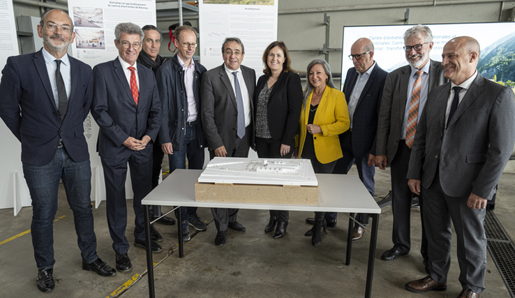 Les dix personnes posent derrière la maquette du futur centre, dans une halle des locaux actuels.